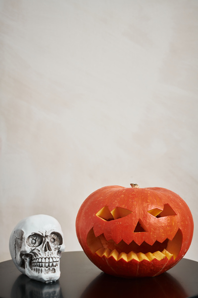 Halloween Pumpkin with Carved Muzzle Stands Next to Skull